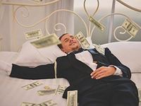 man laying in bed with money around him